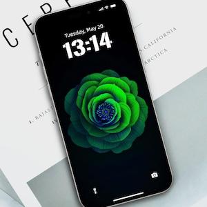 May include: A black smartphone with a green flower on the screen. The time is 13:14 and the date is Tuesday, May 20. The phone is on a white surface with the word "CEREAL" printed on it.