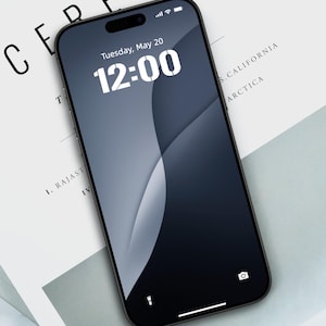 May include: A black smartphone with a dark blue and gray gradient display, showing the time as 12:00 on Tuesday, May 20. The phone is resting on a white paper with the word "CEREAL" printed on it.