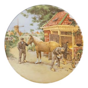 Può includere: Piatto decorativo raffigurante una scena rurale con un cavallo, un fabbro e un uomo in abito marrone. La scena comprende un edificio con tetto rosso, un mulino a vento e un cavallo. Il piatto ha forma rotonda.
