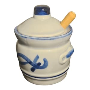 Könnte beinhalten: Eine weiße Zuckerdose aus Keramik mit Deckel und kleinem Holzlöffel. Die Schüssel hat blaue Akzente und einen blauen Rand. Der Deckel hat einen blauen Knopf. Die Schüssel hat einen Griff auf jeder Seite.