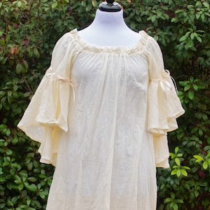 May include: A white off-the-shoulder peasant top with ruffled sleeves and tied bows at the wrists.