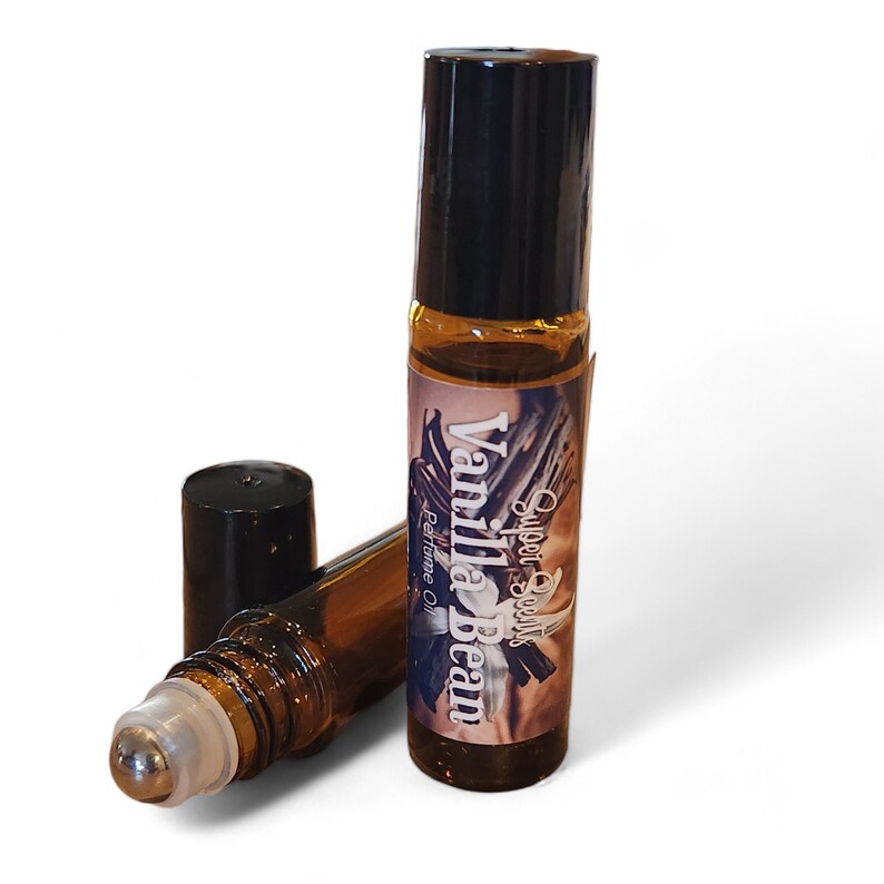 May include: A brown glass roller bottle with a black cap and a label that says "Sweet Scent's Vanilla Bean Perfume Oil".