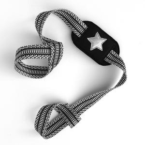 May include: Black and white patterned guitar strap with a black star-shaped patch.