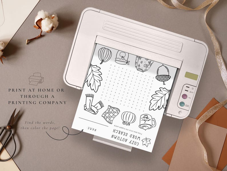 May include: A black and white printable Cozy Autumn word search puzzle sheet is shown inside a white printer. The sheet features fall-themed illustrations and the text "Print at home or through a printing company".