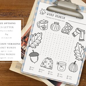 May include: A black and white printable word search puzzle with autumn-themed illustrations, including a mug, pumpkin, and scarf. The paper is held by a silver clipboard. Size options are US Letter (8.5 x 11 inches) and A4 (21 x 29.7 cm).
