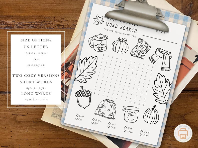 May include: A black and white printable word search puzzle with autumn-themed illustrations, including a mug, pumpkin, and scarf. The paper is held by a silver clipboard. Size options are US Letter (8.5 x 11 inches) and A4 (21 x 29.7 cm).