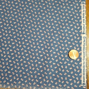 May include: Blue fabric with a repeating pattern of small, pink and white spools. A penny is included for scale. The fabric has the text "Crafted with Pride in USA" and "JOAN KESSLER for Concord Fabrics Inc."
