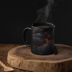 May include: A black ceramic mug with a lava rock design and steam rising from it. The mug is sitting on a wooden cutting board with a tea bag hanging from the rim.