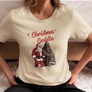 Christmas Cuddles Christmas Tee, Fun Holiday Shirt, Unisex Short Sleeve, Bigfoot Santa T-Shirt, Perfect for Christmas Parties, Unique Gift