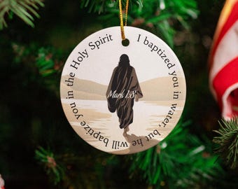 May include: A round, white Christmas bauble with a silhouette of a person walking on a beach. The bauble has the text "Will he baptize you in water, but he will baptize you in the Holy Spirit. I baptized you in water. Mark 1:8"