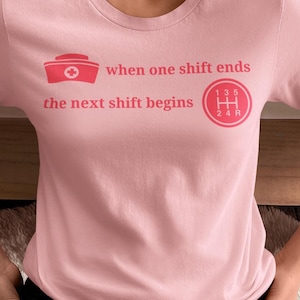 Op de afbeelding: Lichtroze T-shirt met een afbeelding van een verpleegsterskap en een versnellingsbak, met de tekst "when one shift ends the next shift begins". Het T-shirt is gemaakt van zacht materiaal. De tekst en afbeeldingen zijn roodroze.