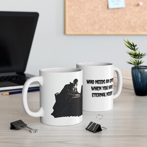 May include: Two white ceramic mugs with black text and a black and white illustration of a person sitting at a desk with a laptop. The text on the mug reads "Who needs an office when you have eternal night."