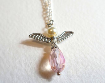 May include: A silver angel pendant necklace with a pink crystal and a white pearl. The necklace is on a silver chain.