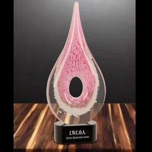 May include: Pink glass award in the shape of a teardrop with a circular opening. The award sits on a black base with the text "I.W.C.O.A. Special Recognition Award".