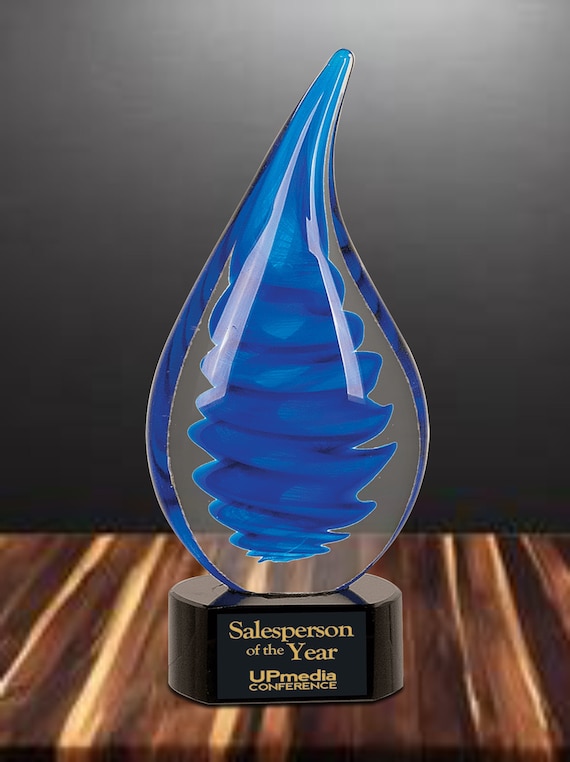 A genuinely hand-blown glass sculpture with a hypnotic blue twist-raindrop pattern, customizable with engraving — the kind of award or keepsake you'd actually want to display.