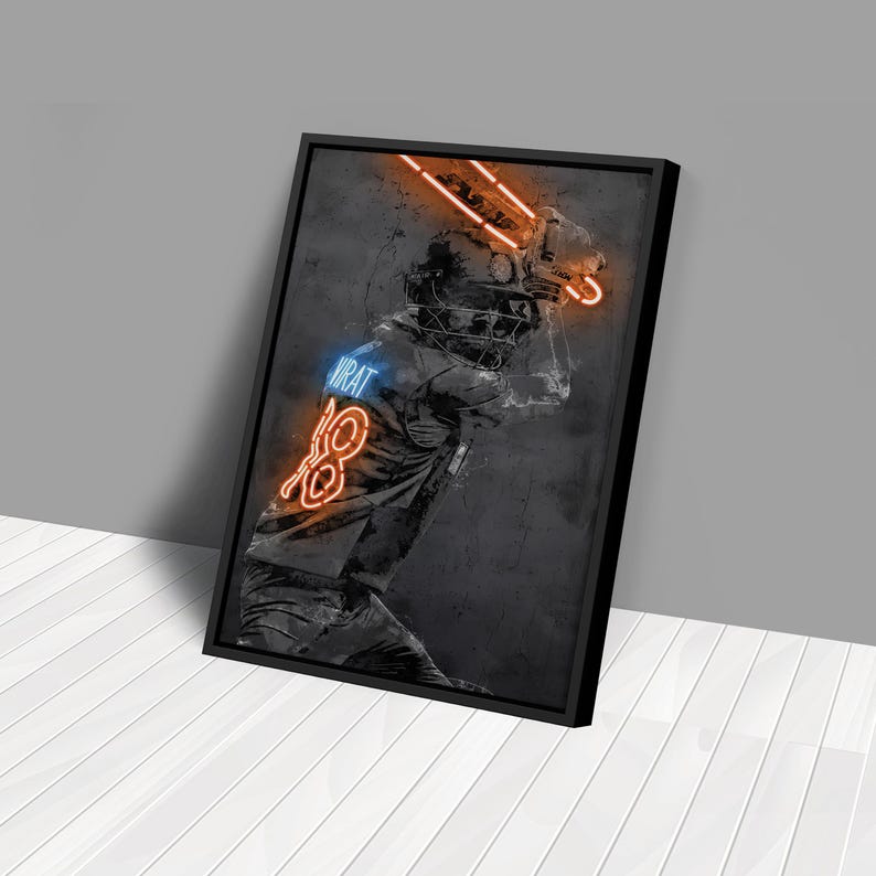 Pu&ograve; includere: Un'illustrazione in bianco e nero di un giocatore di cricket in posizione di battuta con accenti di neon arancione e blu. La maglia del giocatore ha il nome "VIRAT" e il numero "18".