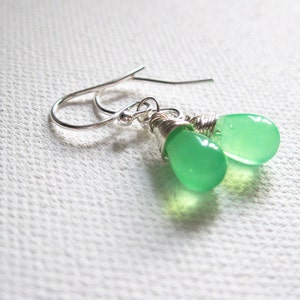 May include: A pair of silver earrings with green gemstone drops. The earrings are made with wire wrapped around the stones.