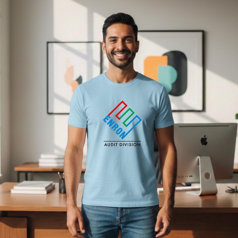 May include: Light blue t-shirt with the text "ENRON AUDIT DIVISION" in a colorful logo design. The shirt is made of a soft material and is suitable for casual wear.