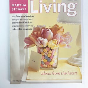 May include: The cover of Martha Stewart Living magazine, February 2004, features a glass filled with heart-shaped candies and a bouquet of pink and yellow tulips. The text includes "ideas from the heart" and a list of recipes and home decor ideas.