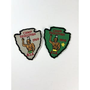 May include: Two vintage Camp Sequoyah patches. One is gray with the year 1969, and the other is green with the year 1970. Both patches feature a Native American figure and the letters "B.S.A."