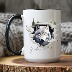May include: White ceramic mug with a black handle. The mug features a wolf's head peeking out of a hole in a forest scene. The name "Jonathan" is printed below the wolf.