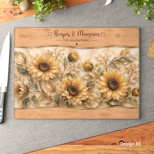 Könnte beinhalten: Rechteckiges Holzschneidebrett mit Sonnenblumenmuster. Auf dem Brett steht der Text "Recipes & Memories - The Wilson Family". Das Design umfasst gelbe Sonnenblumen und grüne Blätter mit einem goldenen Rand.