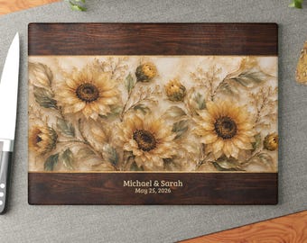 Peut inclure: Une planche à découper rectangulaire avec des bordures en grain de bois brun foncé et un panneau central présentant un motif de tournesols peints. Le texte Michael & Sarah May 25, 2026 est imprimé en blanc sur la partie inférieure en bois.