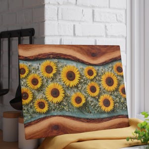Peut inclure: Une planche &agrave; d&eacute;couper rectangulaire avec une bordure en bois &agrave; bord brut en haut et en bas, et un panneau central en r&eacute;sine transparente incrust&eacute; de tournesols jaunes et de petites fleurs blanches sur fond bleu clair.