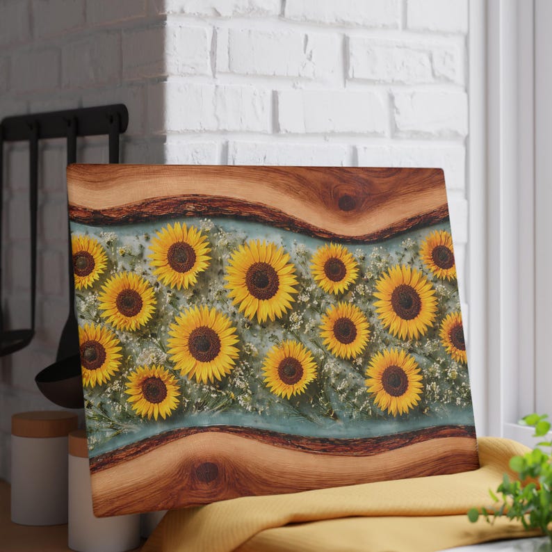 Peut inclure: Une planche &agrave; d&eacute;couper rectangulaire avec une bordure en bois &agrave; bord brut en haut et en bas, et un panneau central en r&eacute;sine transparente incrust&eacute; de tournesols jaunes et de petites fleurs blanches sur fond bleu clair.