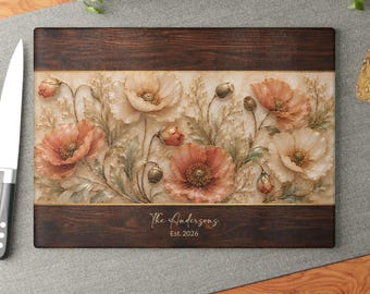 Peut inclure: Une planche à découper rectangulaire en bois avec des bordures en grain de bois brun foncé et un panneau central illustrant des coquelicots pêche et crème. Le texte "The Andersons Est. 2026" est imprimé en blanc sur la bordure inférieure.
