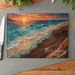 May include: A rectangular glass cutting board featuring a sunset beach scene with turquoise ocean waves crashing onto a sandy shore. The right side displays a dark wood grain pattern with the white text "The Wilsons" and "Est. 2026" printed on it.