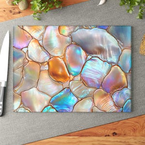 May include: A rectangular cutting board featuring a mosaic pattern of iridescent abalone shell fragments in shades of blue, purple, orange, and white. The surface displays a smooth, glossy finish with distinct dark grout lines between each shell piece.