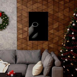 Könnte beinhalten: Ein abstrakter Schwarz-Weiß-Kunstdruck mit einer Vase mit kreisförmiger Öffnung. Das Kunstwerk wird an einer Holzwand mit geometrischem Muster gezeigt. Ein Weihnachtsbaum mit Ornamenten und ein Sofa mit Kissen befinden sich im Vordergrund.