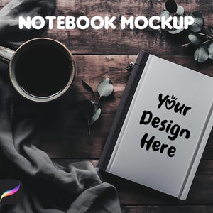 Puede incluir: Un cuaderno blanco con una encuadernación negra y una banda elástica negra. El cuaderno tiene el texto "Your Design Here" escrito en la portada. El cuaderno está sobre una superficie de madera con una taza de café y una rama de vegetación.