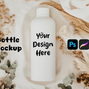 Może przedstawiać: Biała butelka makiety z tekstem "Your Design Here" na białym tle z tkaniny z suszonymi kwiatami i zielenią.