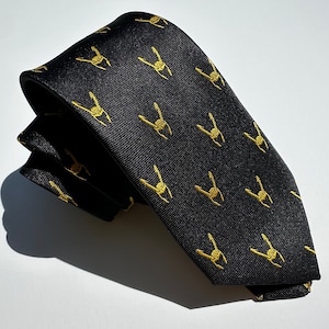 May include: A black silk tie with a repeating pattern of gold-colored rock and roll hand gestures.