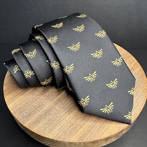 Könnte beinhalten: Eine schwarze Krawatte mit einem sich wiederholenden Muster aus goldenen Triforce-Symbolen.
