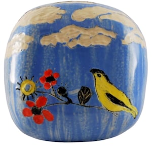 Puede incluir: Un jarrón de cerámica azul con un pájaro amarillo, flores rojas y nubes blancas pintadas sobre él.