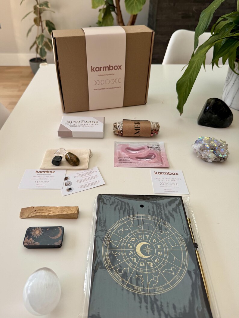 May include: A Karmbox subscription box set containing a cardboard box, a deck of Mind Cards, a sage bundle, a small pouch with three crystals, a Japan Sakura face mask, two informational cards, a palo santo stick, a metal tin, a crystal, and a zodiac journal.