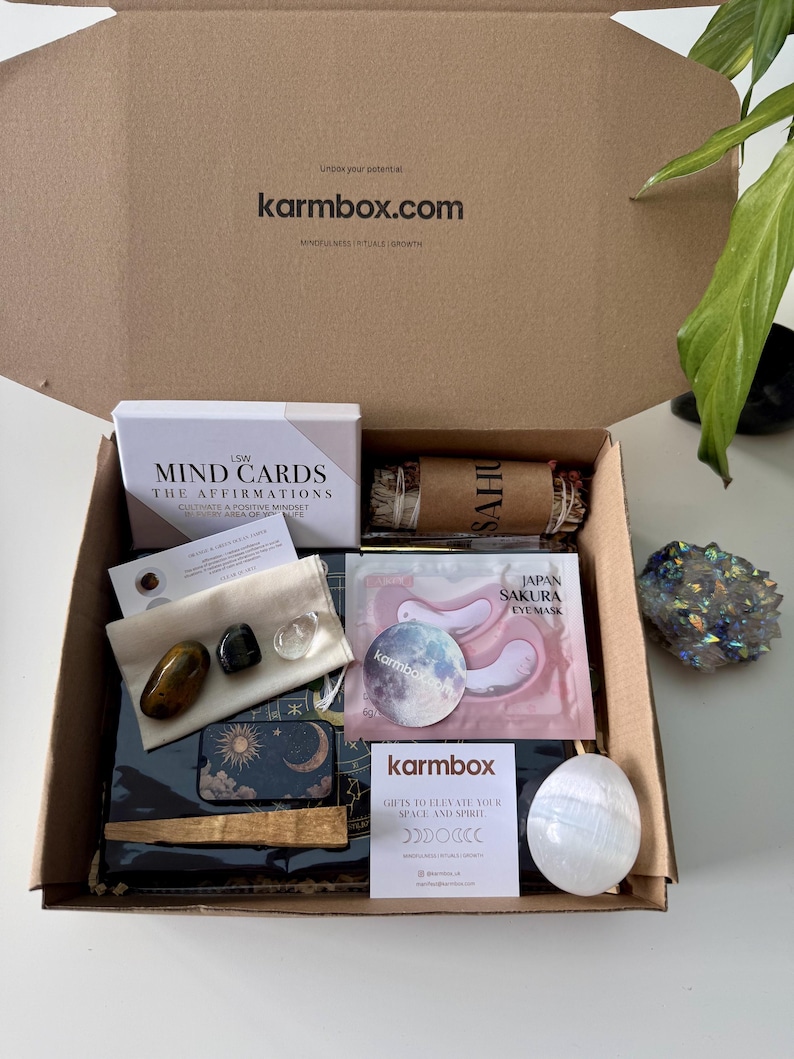 May include: A cardboard subscription box containing LSW Mind Cards, a Japan Sakura eye mask, a bundle of dried herbs, a small pouch with three polished stones, a moon-themed tin, a wooden stick, a white crystal egg, and a Karmbox card.