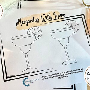 Puede incluir: Una página para colorear imprimible con dos vasos de margarita con limas. El texto "Margaritas With Limes" está en la parte superior de la página. La página es blanca con contornos negros.