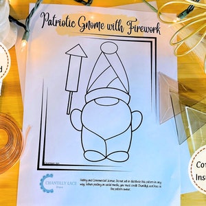 May include: A black and white line art printable pattern of a gnome holding a firework. The text "Patriotic Gnome with Firework" is at the top of the page. The text "Digital Download" is in a circle at the top left of the page. The text "Comes With Instructions!" is in a circle at the bottom right of the page.