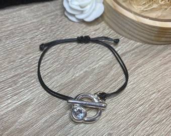 Pulsera ajustable de cordón negro, cierre tipo palanca con pedrería.