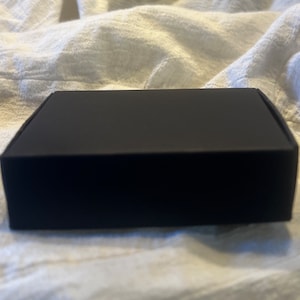 May include: A black cardboard box with a smooth surface.