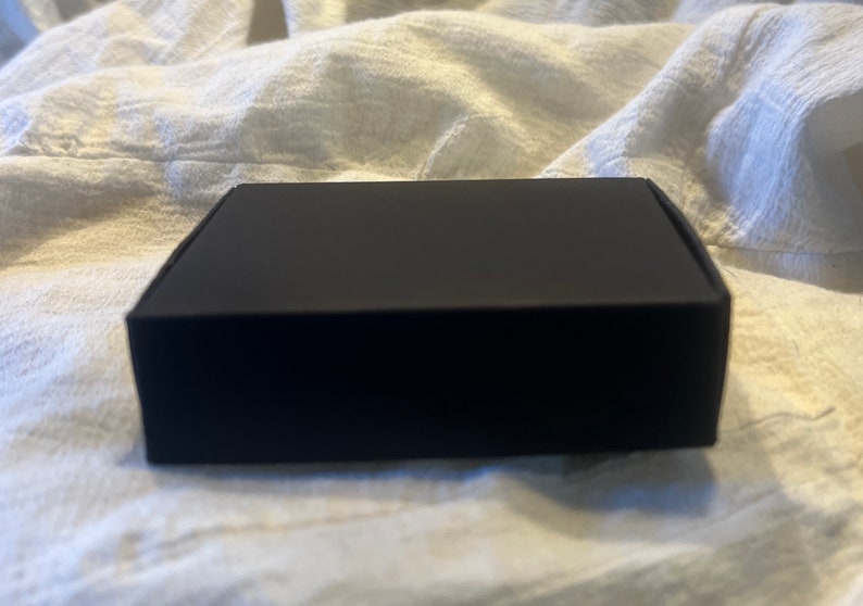 May include: A black cardboard box with a smooth surface.