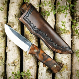 Jacht- en outdoormes gemaakt van 100C6 koolstofstaal met een handvat van gestabiliseerd walnootwortelhout en een leren holster.