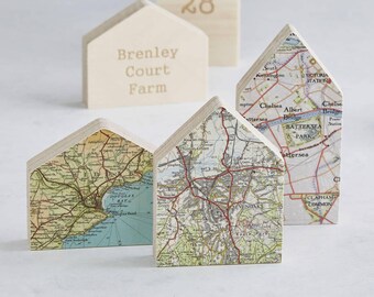 Può includere: Set di quattro ornamenti in legno a forma di casa. Tre degli ornamenti sono decorati con mappe vintage di Londra, Inghilterra. Il quarto ornamento è un blocco di legno con il testo "Brenley Court Farm" e il numero "28" inciso su di esso.