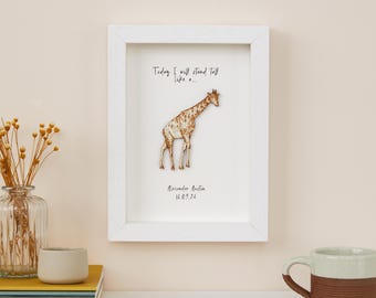 May include: A framed print featuring a giraffe illustration with a white frame. The print includes the text "Today I will stand tall like a..." and the name "Alexander Austin" with the date "16.09.24". The giraffe has a brown and tan pattern.