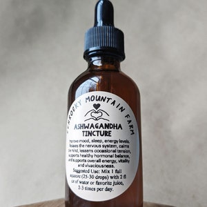 May include: A brown glass bottle with a dropper top and a white label that reads "Rocky Mountain Farm Ashwagandha Tincture". The label also includes instructions for use: "Improve mood, sleep, energy levels. Relaxes the nervous system, calms the mind, lessens occasional tension, supports healthy hormonal balance, and supports overall energy, vitality and vivaciousness. Suggested Use: Mix 1 full squeeze (25-30 drops) with 2 fl oz of water or favorite juice, 2-3 times per day."