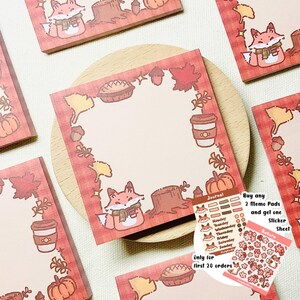 May include: A set of 2 memo pads with a fall theme featuring a fox, leaves, acorns, pumpkins, and a pie. The memo pads are decorated with a red and white checked pattern. The text on the memo pads reads "Journal" and "Only for first 20 orders". There is also a sticker sheet with a fox and flowers.
